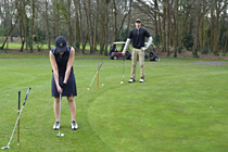 Elegantly chipping-on. Putters leaning on his/her Golf-Rests. Click to enlarge.